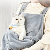 Small dog comfortably resting in a soft dog carrier sling during outdoor walk